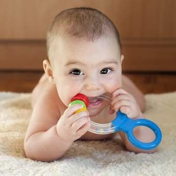 Healthy Home Package Portrait of a cute 6 month old baby, boy or girl, playing with a teething toy.